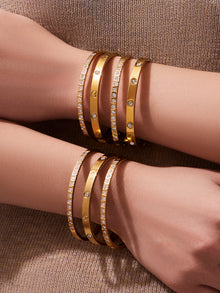 Minimalist gold bangles layered together on the wrists
