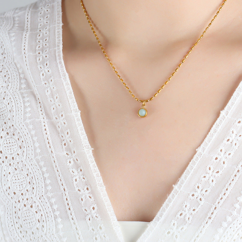Close-up of a model wearing a minimalist round natural stone pendant necklace