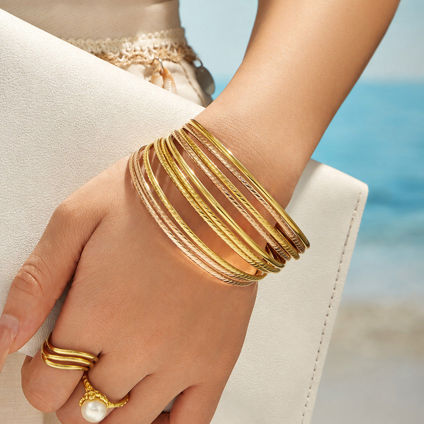 Model wearing layered slim stackable bangles in mixed metal finishes