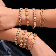 Model wearing a mixed stack of gold zircon tennis and statement bracelets