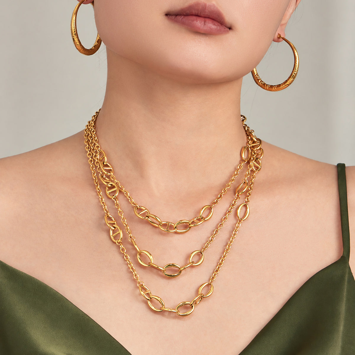 Mixed oval link necklace styled with layered gold chains on model
