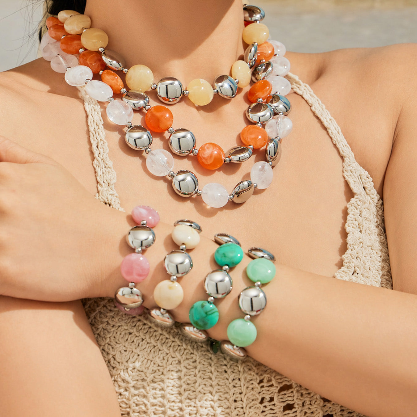 Model wearing a colorful resin bead necklace and stacked bracelet set in a trendy summer boutique styling close-up.
