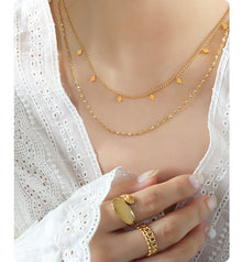 Model wearing a gold-tone double-layer stainless steel necklace with geometric charm details