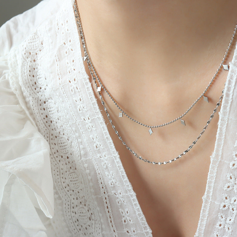 Close-up of a model wearing a gold-tone layered necklace with minimalist geometric charms