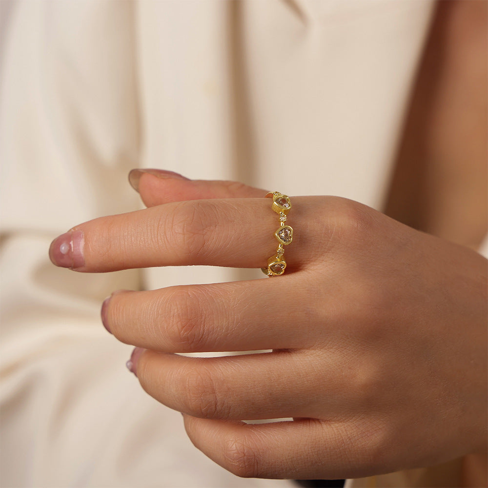 Model wearing a gold-tone band ring with multiple green heart zircon accents