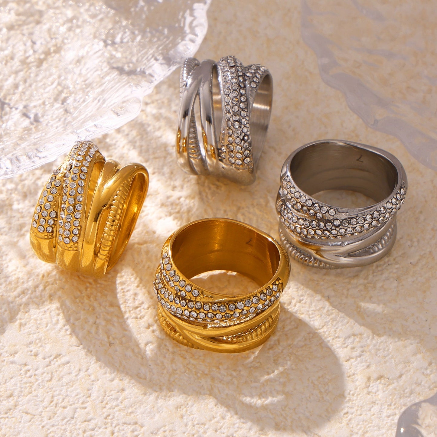 Gold and steel multi-row cubic zirconia statement rings in a styled flat lay