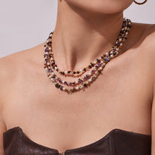 Front view of a model wearing a multi-strand natural stone and pearl necklace