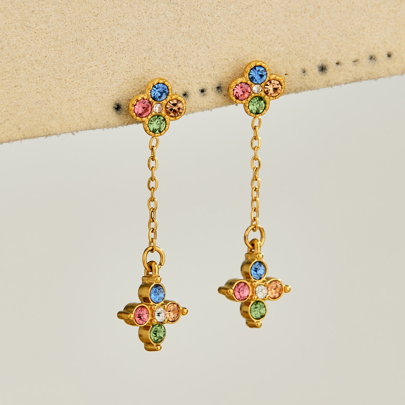 Multicolor cubic zirconia clover drop earrings displayed on a neutral background