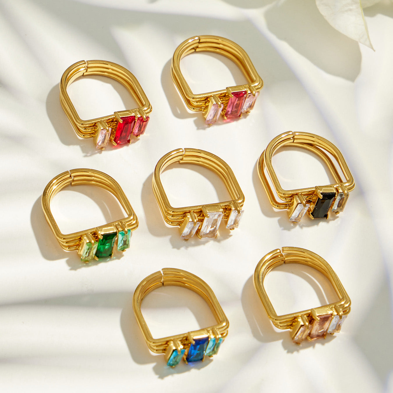 Flat lay of multicolor emerald-cut CZ multi-band rings in 316L stainless steel and 18K PVD gold