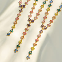 Close-up of multicolor four-petal zircon flower links in a gold-tone setting