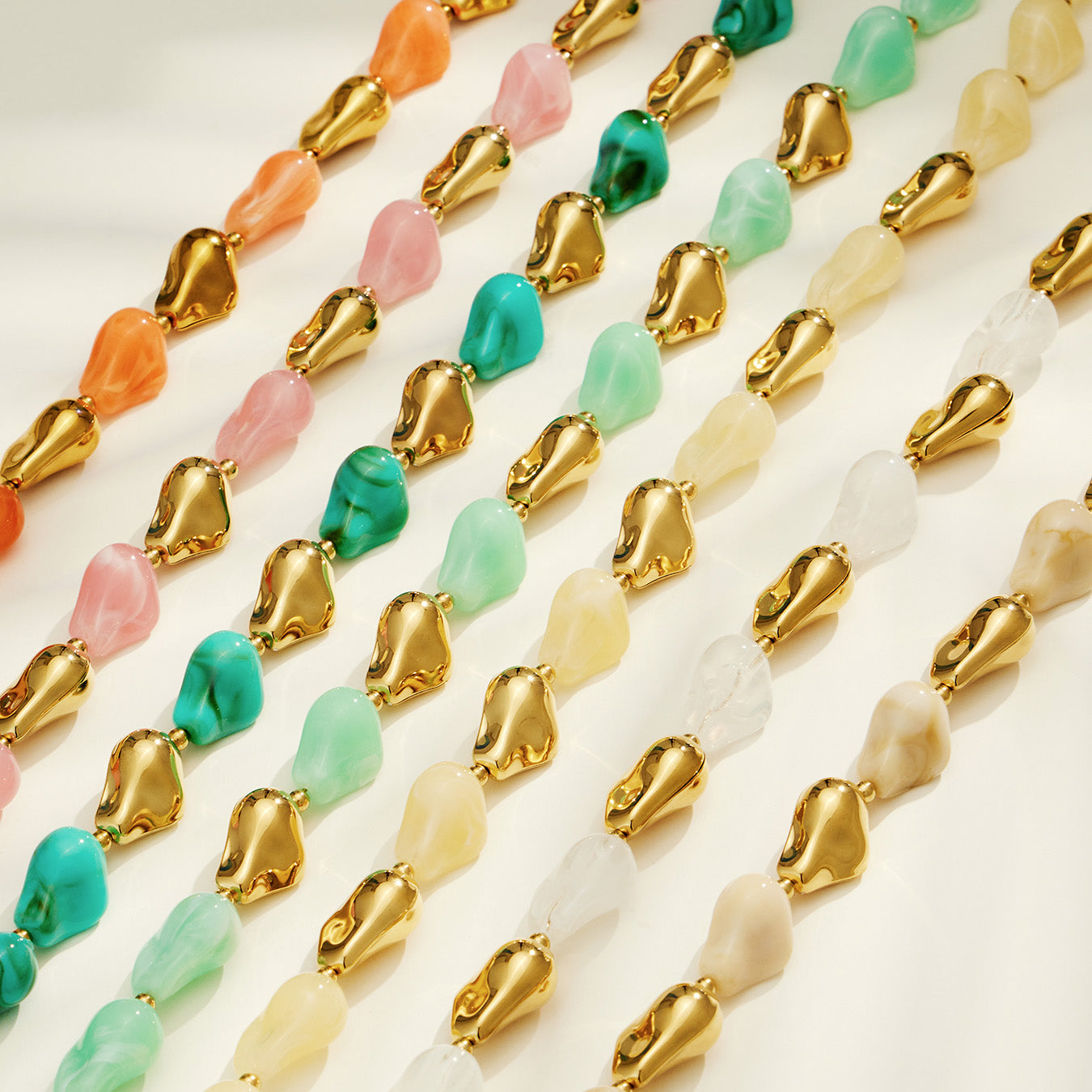 Rows of colorful resin necklace and bracelet designs showing multiple organic bead color options