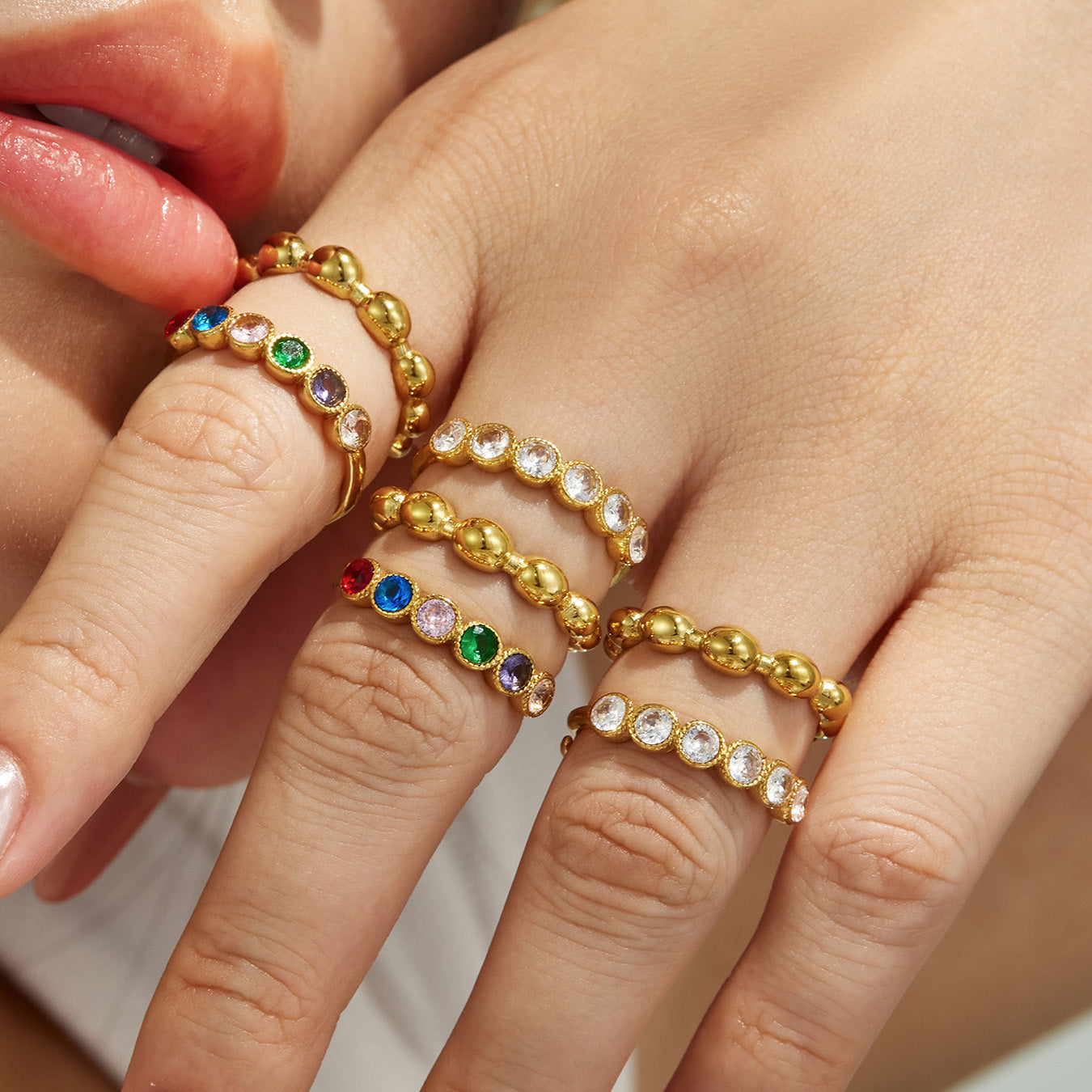 Close-up of multicolor and white CZ beaded rings in 316L stainless steel worn on a model hand