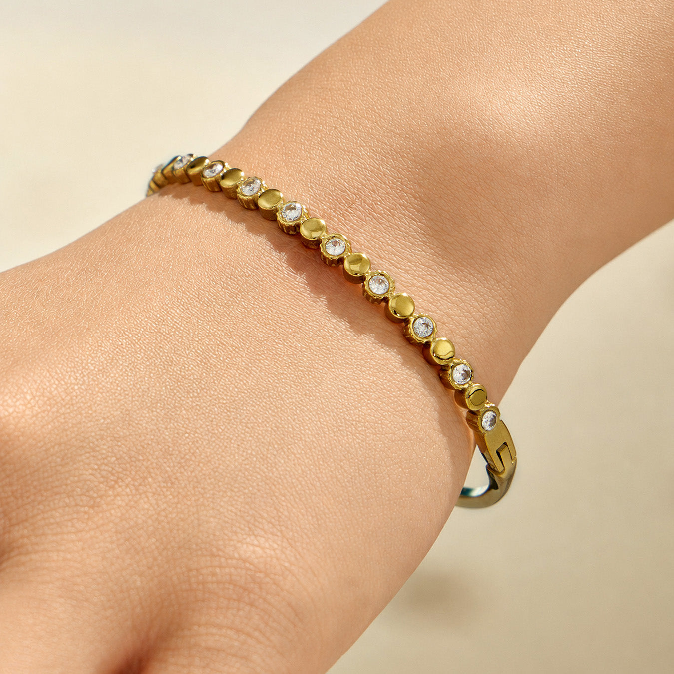 Gold bangle with multicolor zircon accents worn on a model wrist