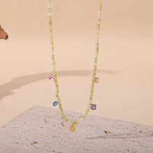 Gold natural stone beaded necklace displayed on a light jewelry presentation background