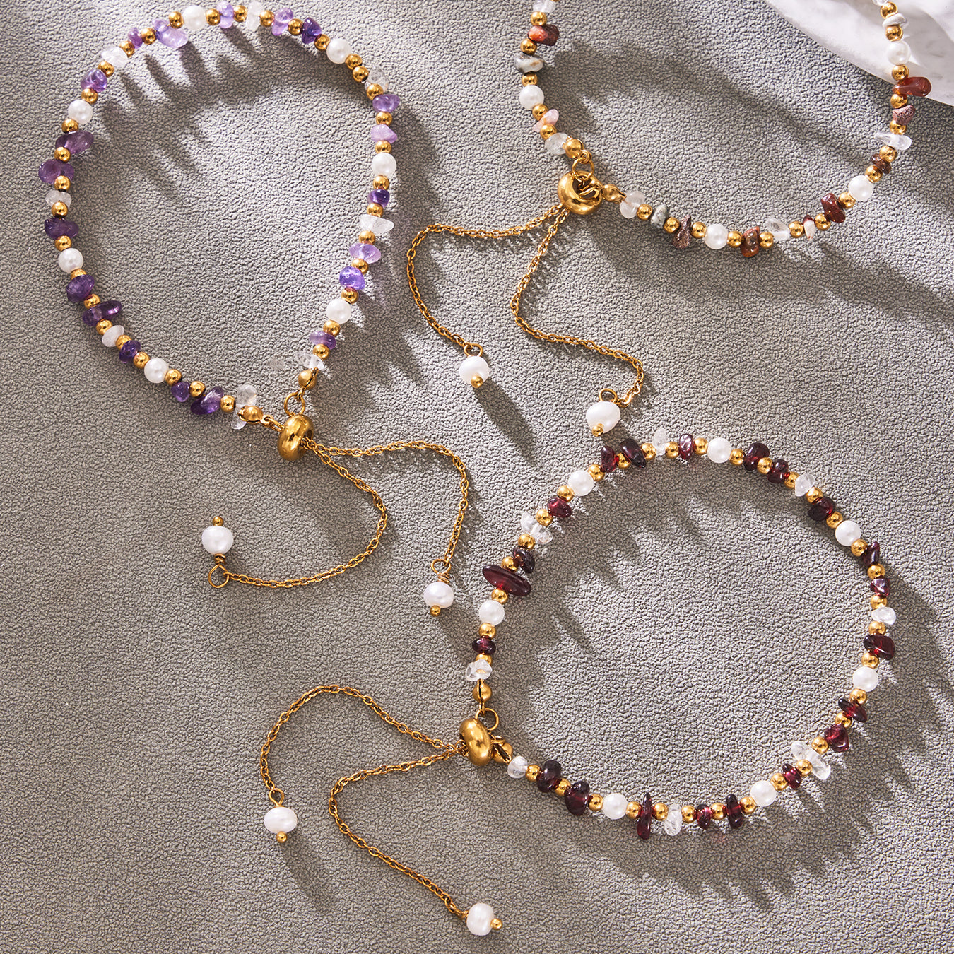 Natural stone necklace and multi-row bracelet displayed together on gray fabric