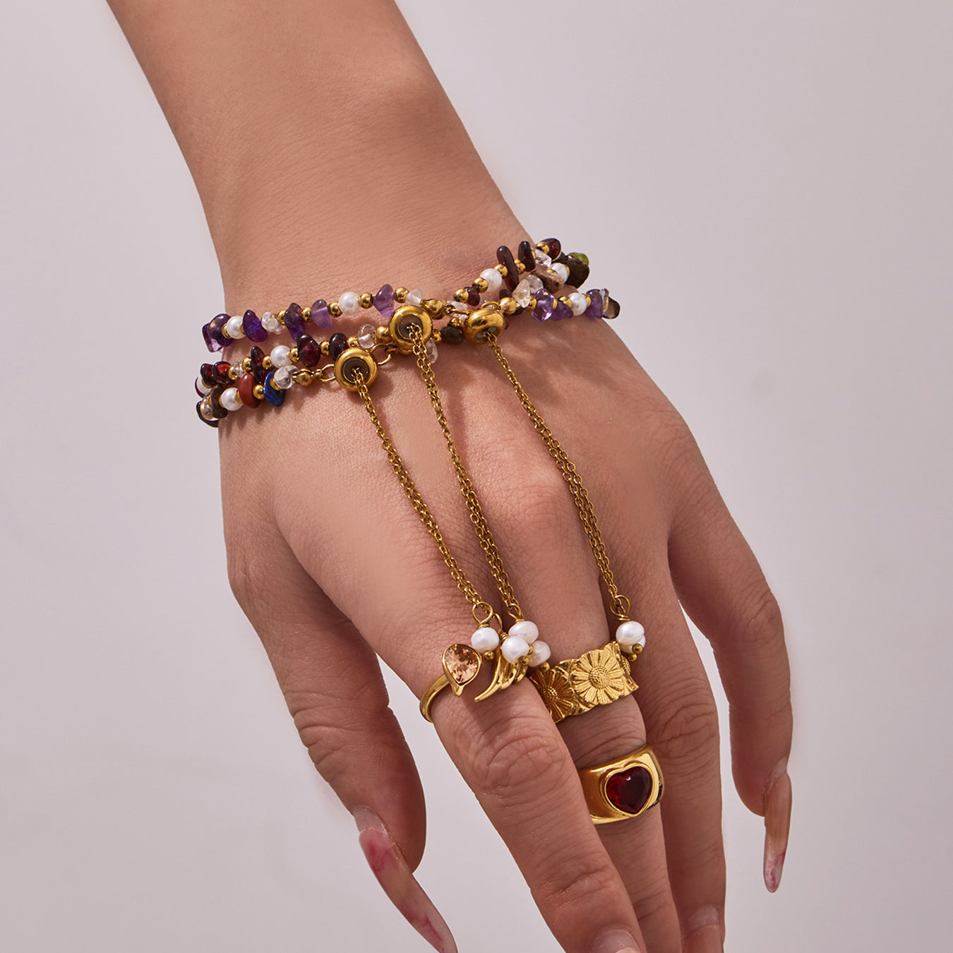 Model wearing a multi-row natural stone and freshwater pearl bracelet with rings