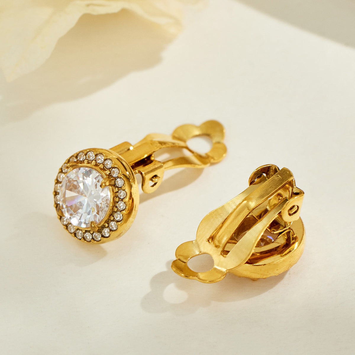 Gold halo clip-on earrings shown from the front and back, highlighting the hinged clip mechanism and round stone settings
