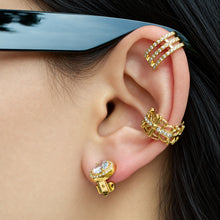 Side view of a gold-tone halo clip-on earring worn on a model's earlobe, featuring a sparkling round center stone