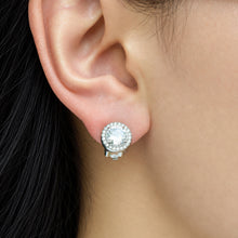 Silver-tone stainless steel halo clip-on earring worn on a model's earlobe with a round clear center stone and pavé border