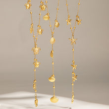 Starfish, turtle and scallop shell Y lariat necklaces displayed together in gold tone