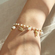 Gold pearl marine charm bracelet with ocean animal details worn on a model wrist