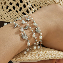 Steel finish ocean charm pearl bracelets layered on a model wrist with marine-inspired charms