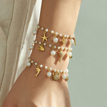 Gold ocean pearl charm bracelets layered on the wrist with sparkling marine-inspired details