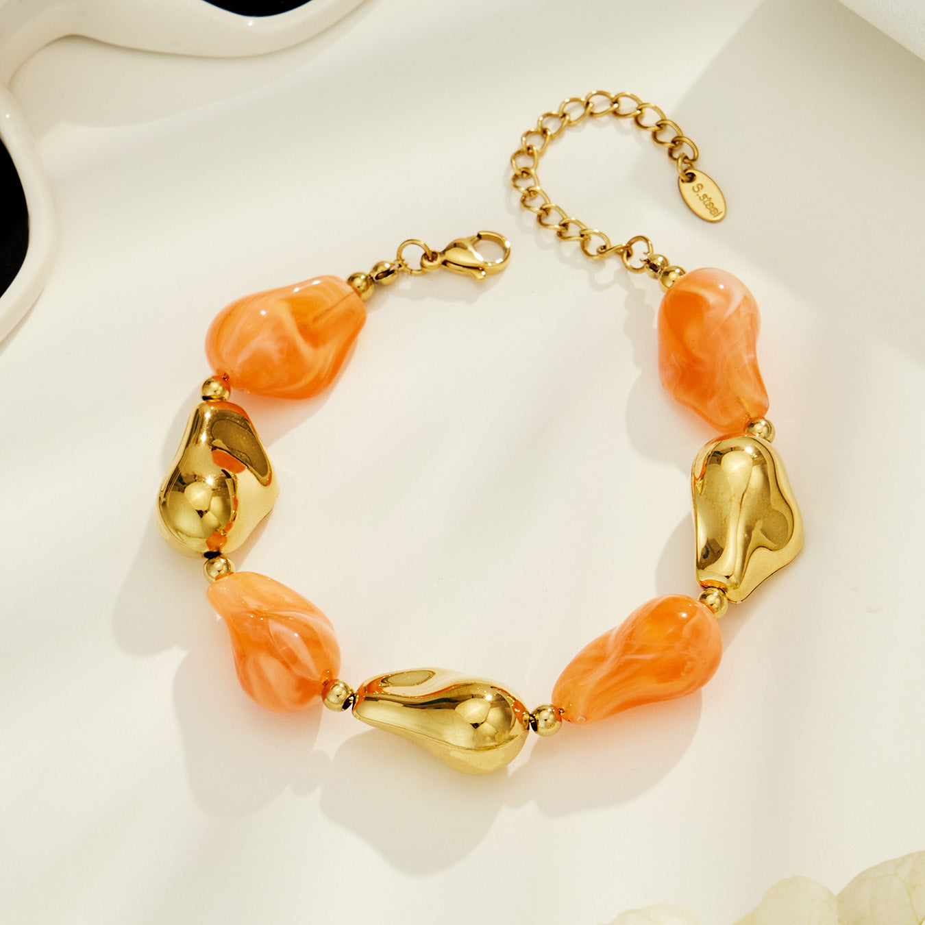 Orange chunky resin bracelet with irregular beads and sculptural gold-tone details