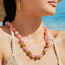 Model wearing a layered orange resin bead necklace styled as a bold summer statement piece.