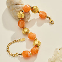 Flat lay of an orange resin bead necklace and matching bracelet set with stainless steel accent beads.
