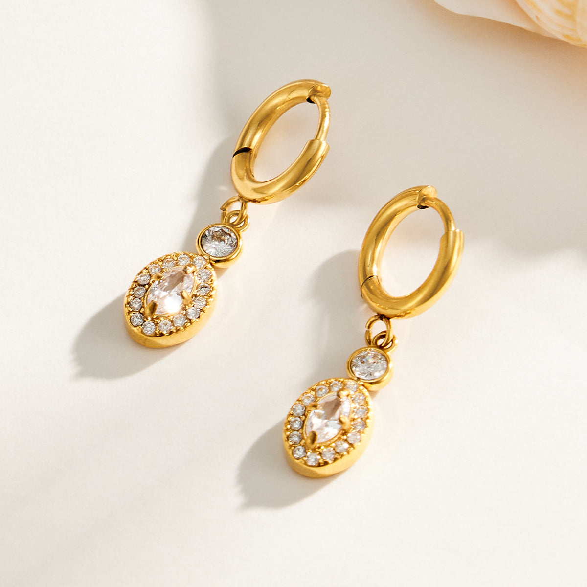 Gold zircon hoop earrings with dangling oval stone charms displayed together