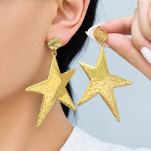 Oversized gold-tone stainless steel star drop earrings shown on model with hand styling
