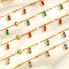 Close up of gold tone glass stone charm necklace with colorful pendant and delicate chain details