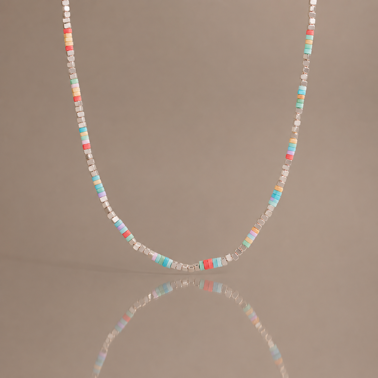 Colorful natural stone beaded necklace with pastel square beads and stainless steel details displayed with soft reflection