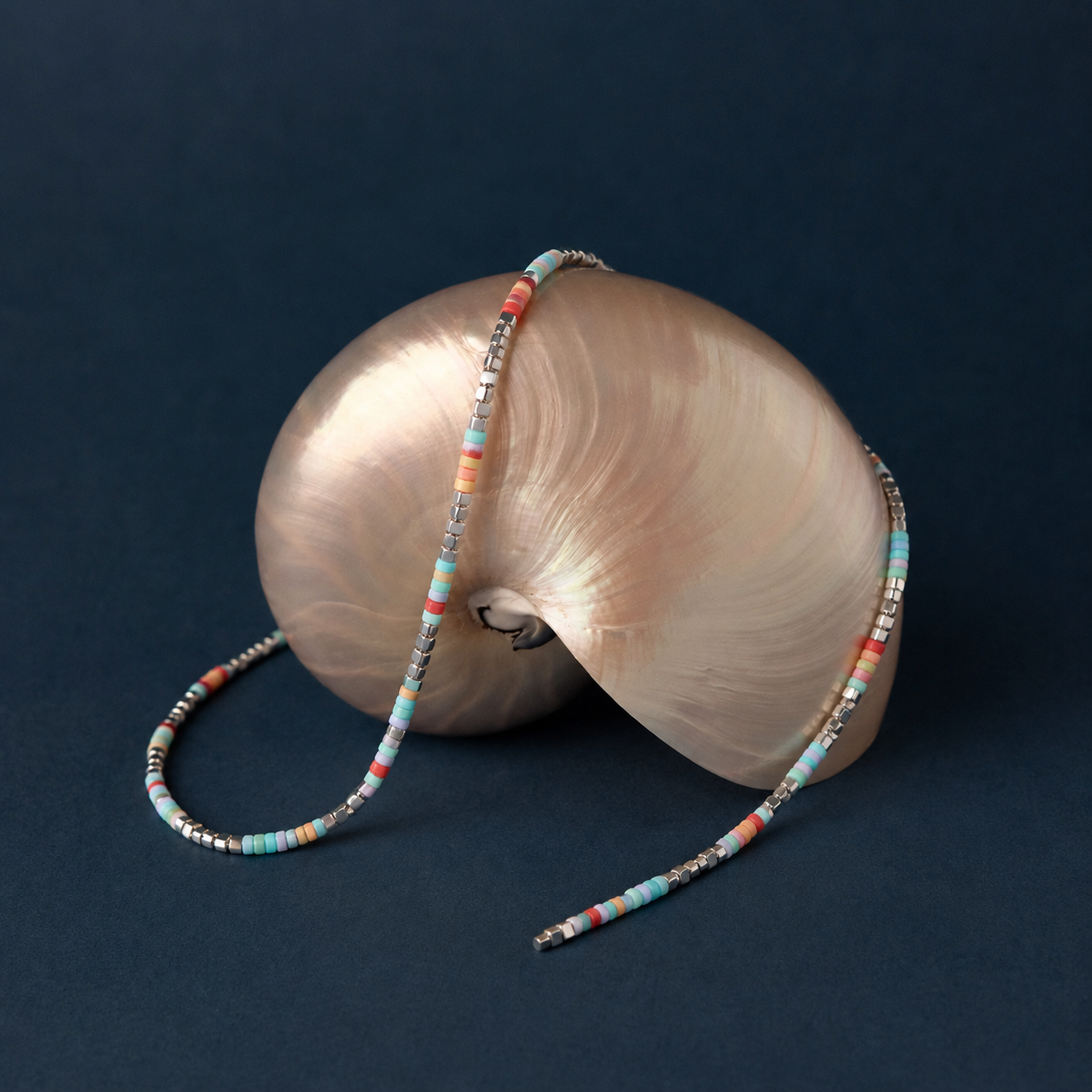 Colorful natural stone heishi bead necklace styled with shell on dark background for resort jewelry and summer boutique displays
