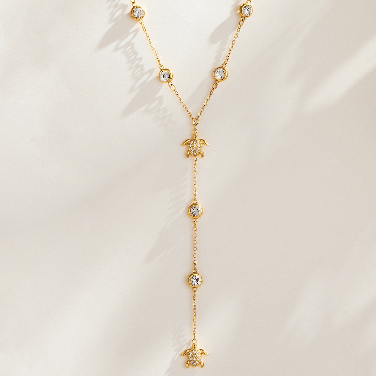 P181 gold-tone sea turtle zircon Y necklace displayed with round stone accents