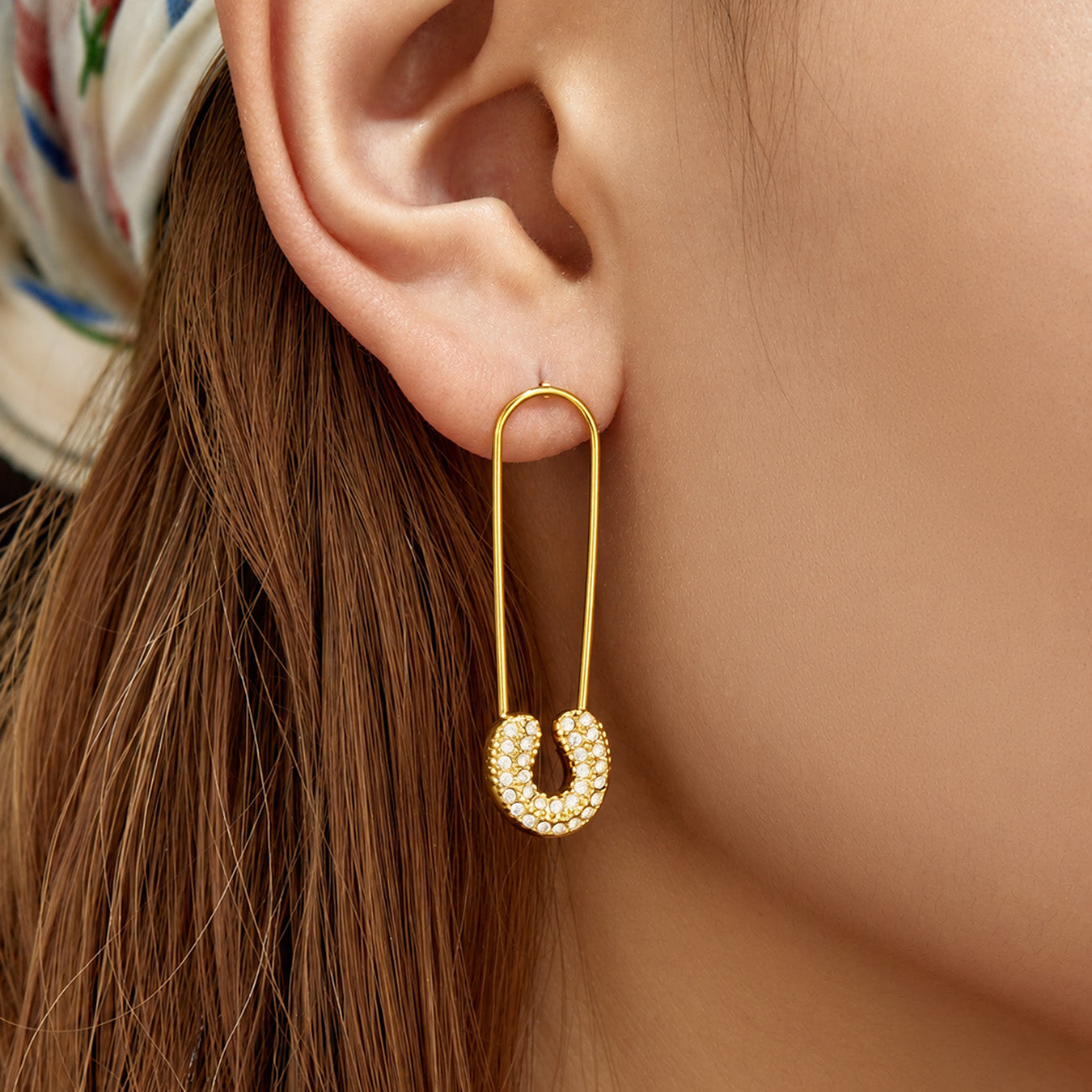 Model wearing gold paperclip-inspired drop earrings from the side