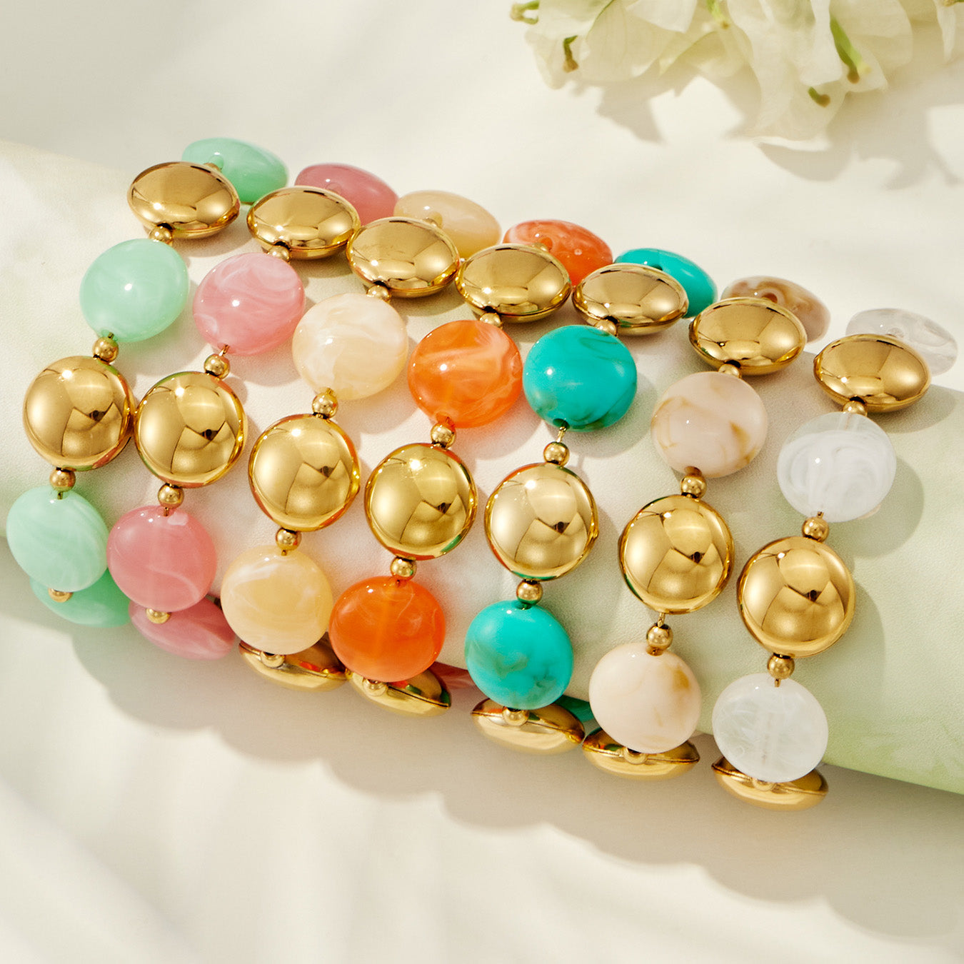 Flat lay of pastel resin bracelet colorways showing assorted trendy bracelet options with gold-tone beads.