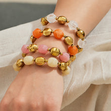 Close-up of pastel resin bead bracelets stacked on the wrist with gold-tone stainless steel accent beads.