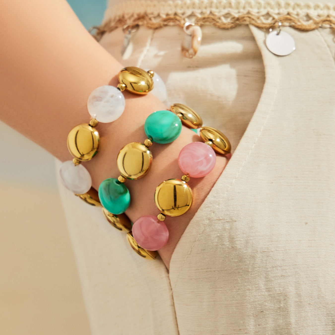 Close-up of pastel resin bead bracelets stacked on the wrist with gold-tone detailing.