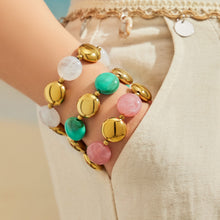 Close-up of pastel resin bead bracelets stacked on the wrist with gold-tone detailing.