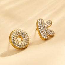 Close-up of pavé gold initial letter stud earrings