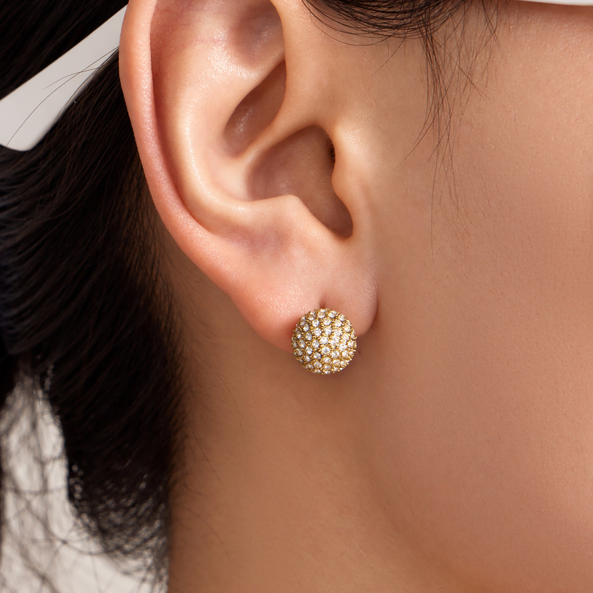 Close-up of pavé zircon ball stud earring worn on model