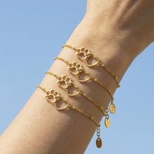 Gold paw heart chain bracelet styled with layered bracelets on the wrist
