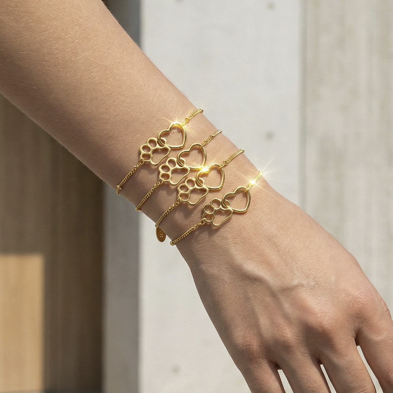 Model wearing a gold paw print heart bracelet on the wrist