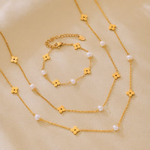 Freshwater pearl clover necklace and bracelet arranged together in a coordinated gold jewelry flat lay