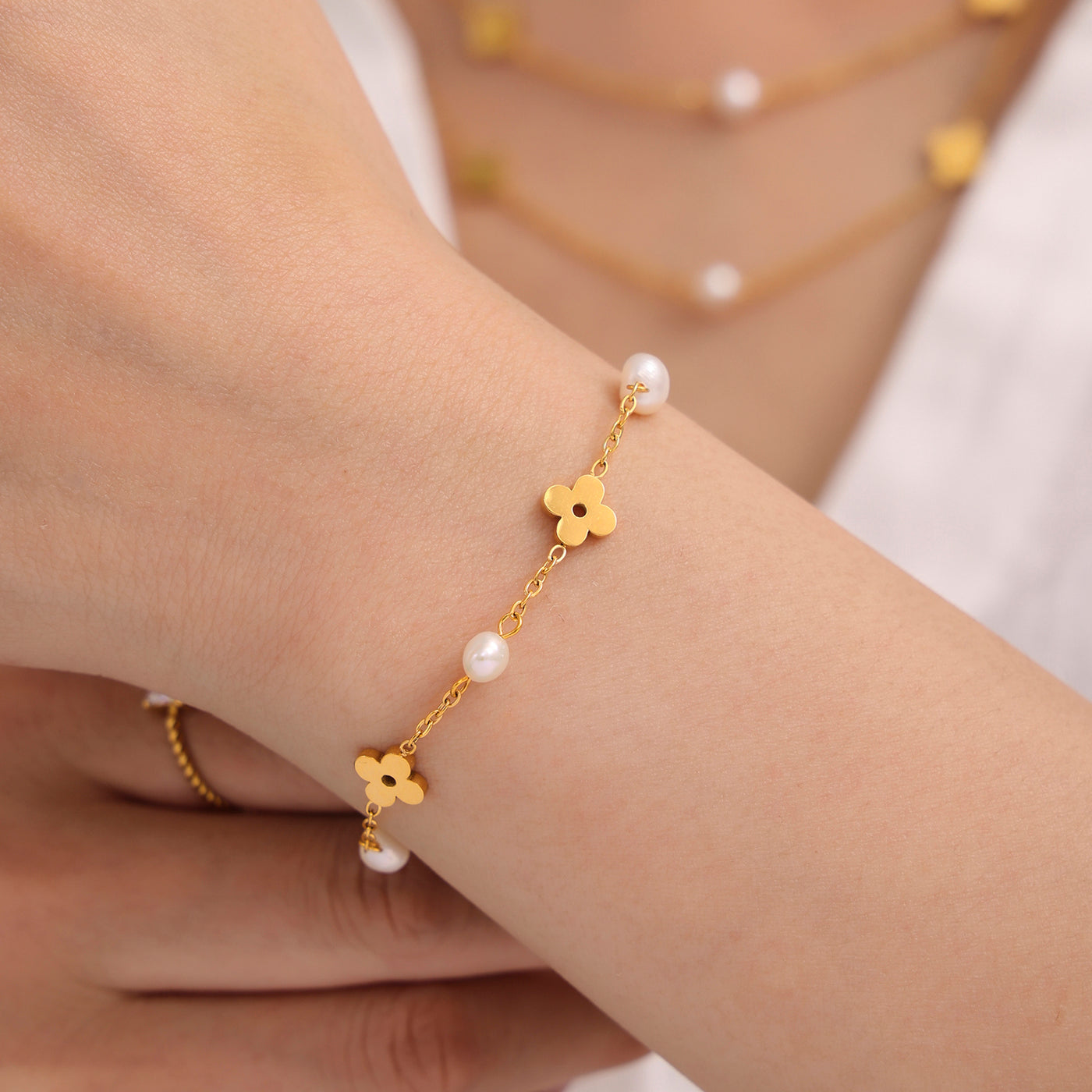 Close-up styling of a freshwater pearl clover necklace and matching bracelet in gold tone
