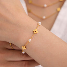 Close-up styling of a freshwater pearl clover necklace and matching bracelet in gold tone
