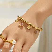 Pink clover beaded charm bracelet worn on a model hand with gold rings