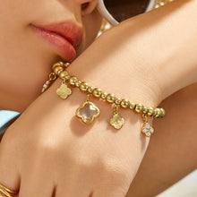 Close-up of a pink four-leaf clover charm bracelet worn on a model wrist